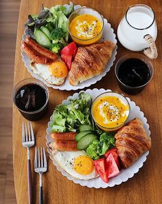 two plates with breakfast foods on them sitting on a table