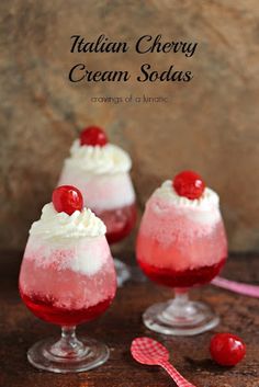 three glasses filled with ice cream and cherries on top of a wooden table next to a