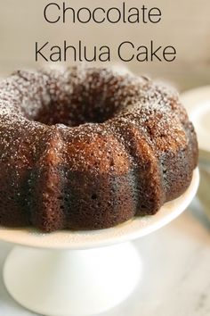 a chocolate kahlua cake sitting on top of a white cake plate with powdered sugar