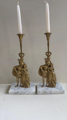 two brass candlesticks with an elephant and rider on marble bases, each holding a candle