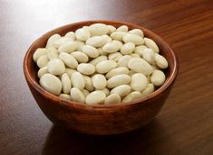 a wooden bowl filled with white beans on top of a table