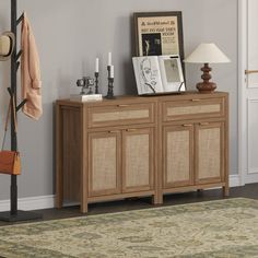 a living room with a rug, lamp and pictures on the sideboard in it