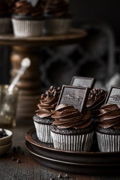 cupcakes with chocolate frosting on a plate next to coffee beans and other dessert items