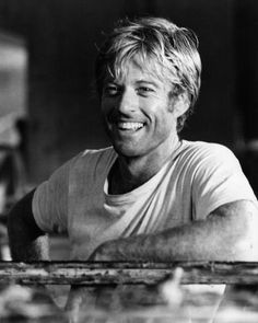 a black and white photo of a man sitting at a table with his arms crossed