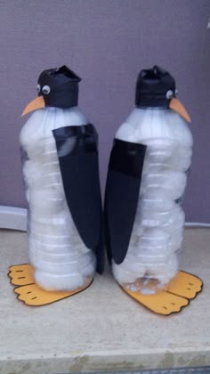 two penguins made out of water bottles sitting on top of a counter