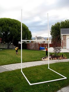 a soccer goal in the middle of a yard with two people playing ball on it