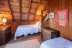 two beds in a room with wooden walls