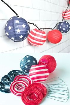 patriotic paper lanterns hanging from a string on a white brick wall with red, white and blue decorations