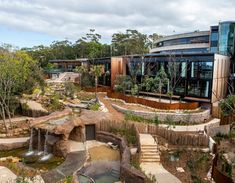 an aerial view of a building with trees in the foreground and water running through it