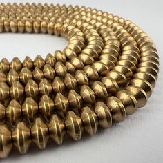 A strand of brass bicone spacer beads. 145 beads 24" of beads 60cm 7mm diameter 4mm tall 2mm hole Focal Beads, Oct 11, Spacer Beads, Halloween Shopping, Seattle, Accessory Gift, Electronic Accessories, Brass, Craft Supplies