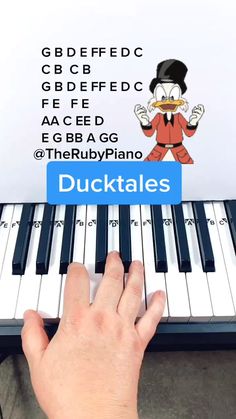 a person is playing the piano with their hand on it and there's an image of ducktales