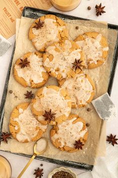 cookies with white icing and star anise sprinkles on parchment paper