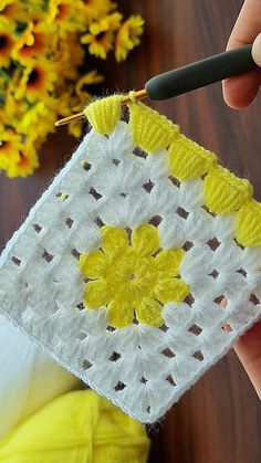 someone is crocheting a square with yellow flowers