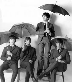 the beatles are holding umbrellas while posing for a photo in front of a white wall