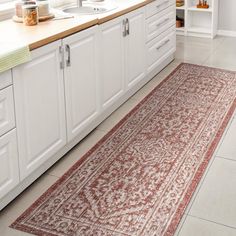 a bathroom with white cabinets and a red rug on the floor in front of it