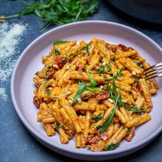 a white plate topped with pasta covered in sauce and garnished with green herbs