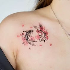 a woman's shoulder with two koi fish and flowers on it