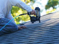 a man is painting the roof of a house with a paint roller and an airbrush