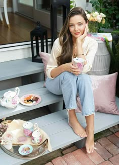 a woman sitting on a bench holding a cup