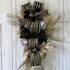 a black and gold christmas ornament hanging on a white wooden wall with the letter n