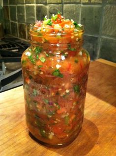 a jar filled with lots of food sitting on top of a wooden table next to a stove