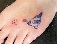 a small blue bird and apple tattoo on the foot