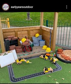 a play area with toys and construction equipment on the ground in front of a fence