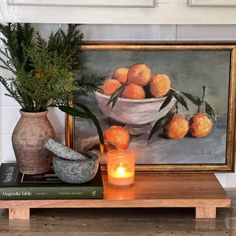 there is a painting on the wall next to a vase with oranges in it