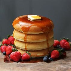 a stack of pancakes with syrup and strawberries