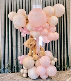 a teddy bear sitting on top of a bunch of balloons