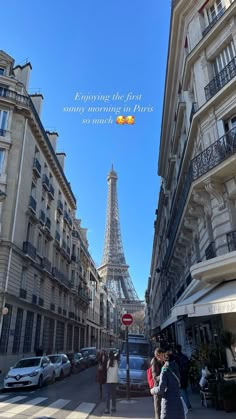 the eiffel tower is in the distance with people walking on the sidewalk below