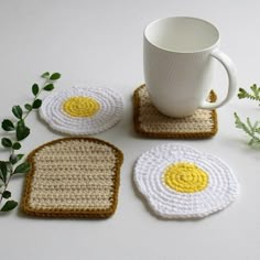 three crocheted coasters with two fried eggs on them next to a coffee cup