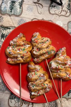 a red plate topped with donuts covered in frosting and sprinkles