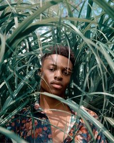 a woman standing in the middle of some tall green grass and looking at the camera with an intense look on her face