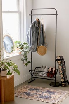 a coat rack with shoes and purses on it next to a potted plant