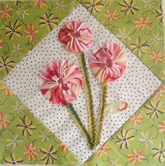 two pink flowers sitting on top of a green and white cloth