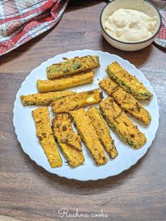 fried zucchini sticks on a white plate next to a bowl of yogurt