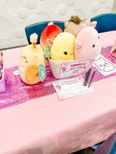 there are stuffed animals sitting in the basket on the pink table clothed tablecloth