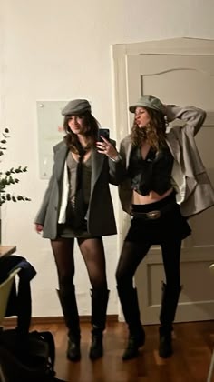 two young women standing next to each other on a hard wood floor in front of a white wall