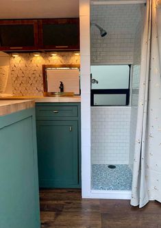 a small bathroom with blue cabinets and white tile on the walls, along with wood flooring