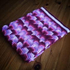 a purple and white crocheted dishcloth sitting on top of a wooden table