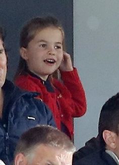 a man and child sitting next to each other in the stands at a soccer game