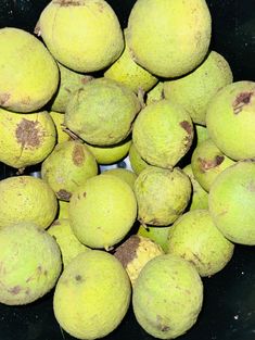 a pile of green fruit sitting on top of a black table