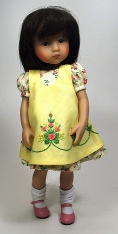 the doll is wearing a yellow dress with flowers on it