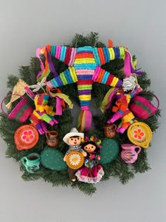 a wreath with many colorful items on it and a stuffed animal hanging from the front