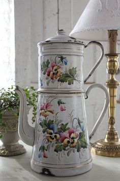 a white tea pot sitting on top of a table next to a lamp