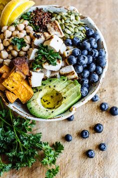 a bowl filled with blueberries, avocado, nuts and other food items