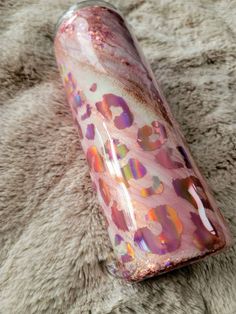 a pink and gold flask sitting on top of a fur covered floor