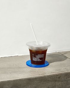 a plastic cup with a straw in it sitting on top of a blue plate next to a white wall