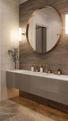 a modern bathroom with marble counter tops and gold accents on the mirror above the sink